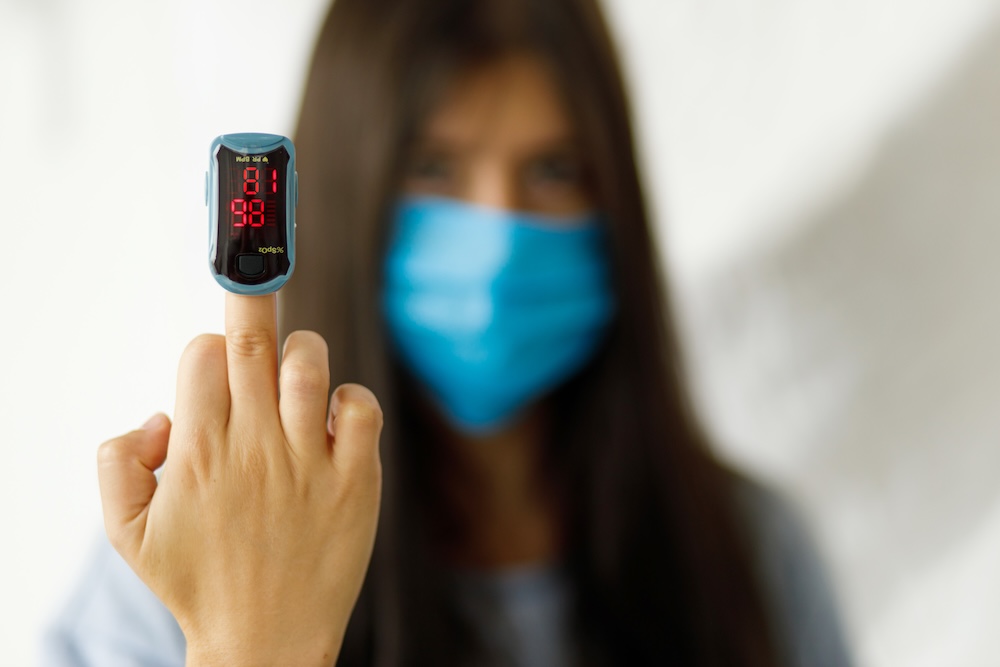 Person misst zu Hause mit einem Pulsoxymeter am Finger ihre Gesundheitswerte