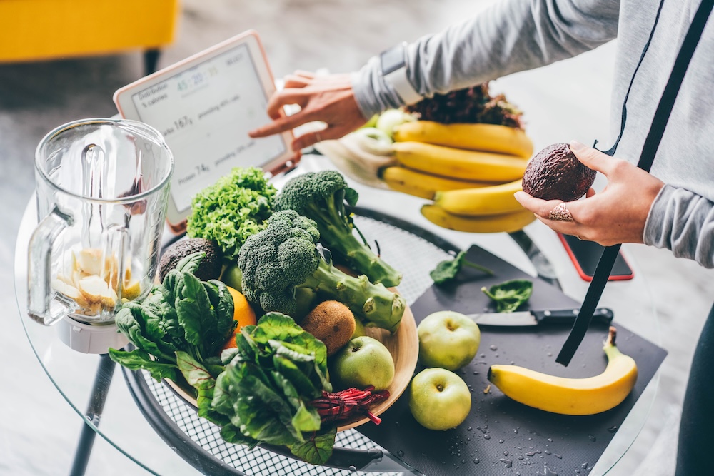 Frau nutzt ein Tablet mit einer Ernährungs-App zur Kalorien- und Glukoseauswertung