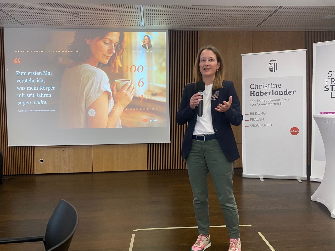 Dr. Gerhilt Kusatz spricht mit Mikrofon vor einer Präsentationsleinwand bei der #BeWirkwerkstatt 2030